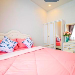 Un dormitorio con una gran cama rosa con almohadas en BreezyS Pool Villa, en Nong Prue