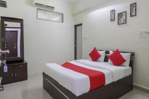スーラトにあるCollection O Shyam Vatika Banquet And Roomsのベッドルーム1室(大型ベッド1台、赤い枕付)