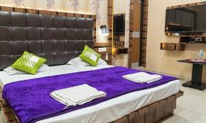 a large bed with purple sheets and green pillows at FabHotel CM Palace I in Varanasi