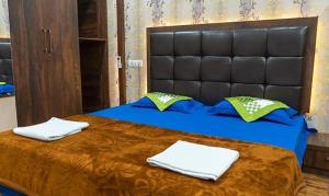a bed with a black headboard and two towels on it at FabHotel CM Palace I in Varanasi