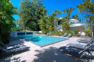 a swimming pool with chairs and a house at Whispering Palms - Beachfront Port Douglas in Port Douglas