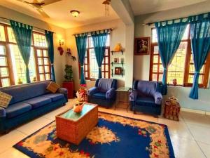 a living room with blue couches and a rug at Rashmi Cottage in Dagshai