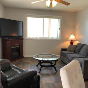 a living room with a couch and a table and a tv at Sun Beach Motel in Osoyoos