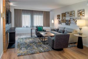 a living room with a couch and chairs and a television at Sheraton Westport Plaza in Maryland Heights