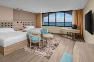 ダル・エス・サラームにあるDelta Hotels by Marriott Dar es Salaamのベッド、デスク、テーブルが備わる客室です。