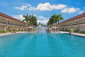 a pool at a resort with chairs and umbrellas at Four Points by Sheraton Palawan Puerto Princesa in Sabang