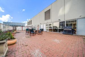 a patio with tables and chairs in front of a building at Canberra 1-Bed with Pool, Gym, BBQ & Tennis Court in Canberra