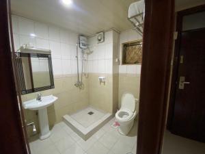 a small bathroom with a toilet and a sink at La Grande Hotel in Kampala