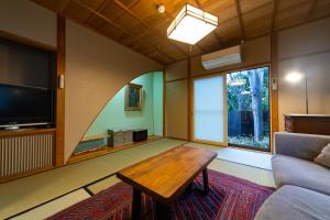 a living room with a couch and a table and a tv at Ryokan Fukinoya in Yufuin