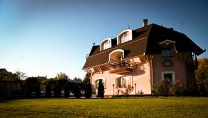 une grande maison avec un toit sur une pelouse dans l'établissement Muschel Panzió, à Keszthely