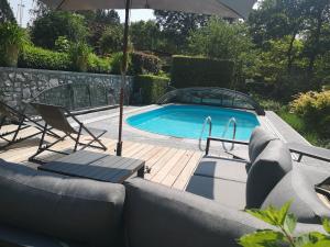 a pool with a couch and chairs and an umbrella at Ardenne BnB suite 1 à 4 personnes in Marche-en-Famenne