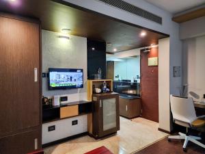 a living room with a television and a kitchen at Dimora Hotels And Resorts in Trivandrum