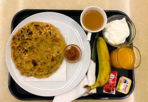a black tray with a plate of omelet and a banana and other food at One Infinity Residency in kolkata +19 photos