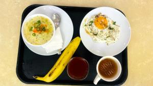 a black tray with two plates of food and a banana at One Infinity Residency in kolkata