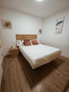 una camera da letto con un grande letto bianco e pavimenti in legno di Duplex labradores centro 8PAX, PARKING INCLUIDO a Logroño