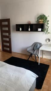 Cette chambre comprend une chaise, une table et un bureau. dans l'établissement Apartament Ponikwoda, à Lublin