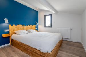 a bedroom with a large bed with a blue wall at Plaines-Provence Spa&Sauna in Digne-les-Bains
