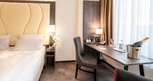 a hotel room with a bed and a desk with a bottle of champagne at Best Western Plaza Hotel Mannheim in Mannheim