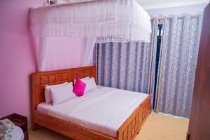 a bedroom with a bed with white sheets and pink pillows at Twin towers hotel in Kampala