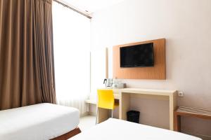 ein Hotelzimmer mit einem Schreibtisch und einem TV an der Wand in der Unterkunft Neo Cempaka Hill Hotel Jember in Jember