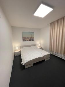 a white bedroom with a bed and two night stands at 2 Bedroom Apartment with Garage in Sandanski