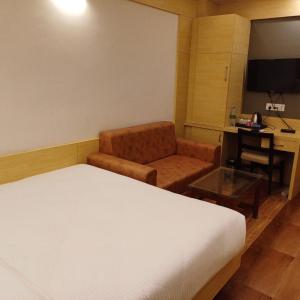 a hotel room with a bed and a chair and a desk at Hotel Taj Akash in Deoghar