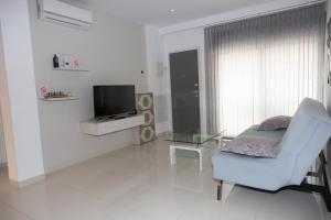 a white living room with a chair and a tv at Playa Elisa Bay app 411 in Pilar de la Horadada