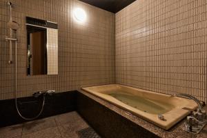 a bathroom with a bath tub and a mirror at M4 design hotel in Tokyo