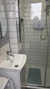 y baño blanco con lavabo y ducha. en Connemara Lake View Apartment, en Camus Eighter