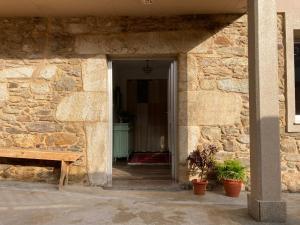 una entrada a un edificio de piedra con un banco de madera en Apartamento en Casa Oliveros, Razo, en A Coruña