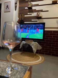 a glass of wine sitting on a table with a television at Nandi Private Residence, Bohemian Hill View Villa in Devanahalli-Bangalore