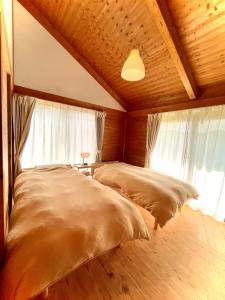 2 łóżka w pokoju z drewnianymi sufitami i oknami w obiekcie Gubo 里山ヴィレッジ 白木 w mieście Katsu’ura