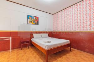 a bedroom with a bed and a red and white wall at Seruni Guest House Near Alun Alun Lembang Mitra RedDoorz in Lembang