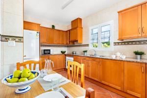 uma cozinha com armários de madeira e uma mesa com uma tigela de fruta em Villa Toymi by Villa Plus em Cala Blanca