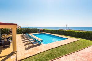 a swimming pool with chairs and the ocean in the background at Villa Mediterraneum by Villa Plus in Cala en Forcat
