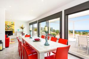 a dining room with a table and red chairs at Villa Dolce Vita by Villa Plus in Alaior