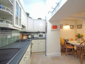 a kitchen with white cabinets and a dining table at Y Bwthyn Newport in Newport Pembrokeshire