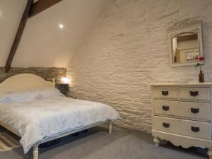 a bedroom with a bed and a stone wall at Ty Cam Abercych in Abercych