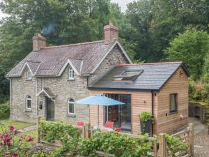 a stone house with an umbrella in front of it at Ty Cam Abercych in Abercych