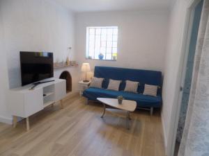 a living room with a blue couch and a tv at Bon Repos 2 in Torroella de Montgrí