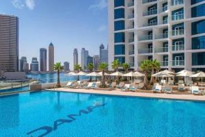uma piscina com cadeiras e guarda-sóis e um edifício em Studio Apartment in DAMAC Maison Prive Business Bay - High Floor em Dubai