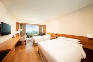 a hotel room with two beds and a television at WE Hotel Jeju in Seogwipo