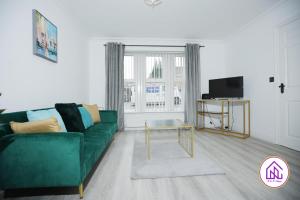 a living room with a green couch and a tv at Milestone House, Large Modern House, Free Parking in Cardiff