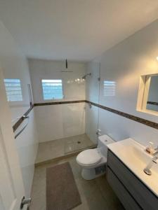 a white bathroom with a toilet and a sink at New* Tropical Modern Townhouse in SXM in Simpson Bay