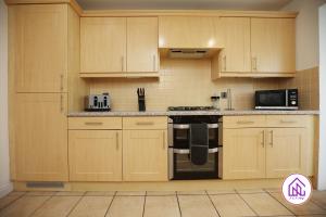 a kitchen with wooden cabinets and a stove top oven at Milestone House, Large Modern House, Free Parking in Cardiff