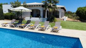 a group of chairs and an umbrella next to a pool at Villa Clara in Cap d'en Font