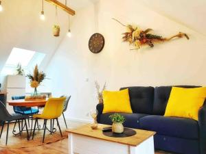 sala de estar con sofá azul y almohadas amarillas en Logement cosy et confortable., en Thourotte