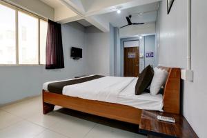 1 dormitorio con 1 cama grande con sábanas blancas en OYO Hotel Sama Residency, en Vadodara