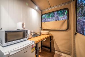 una cocina en una cabaña con barra y microondas en DeluxeQueenSafariTent1, en Nelly Bay