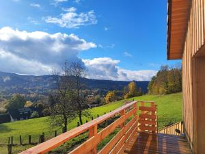 een houten terras met uitzicht op een groen veld bij Refuge au coeur des Vosges in Aumontzey